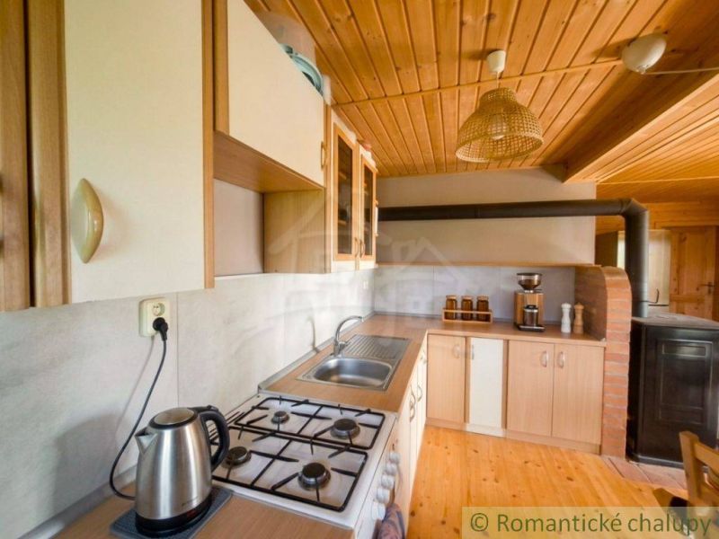 A kitchen with wooden decor in a family house with a gas stove and a wooden ceiling.