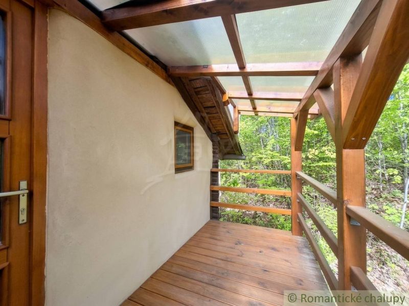 A wooden terrace of a family house in Cinobana surrounded by greenery and forest.