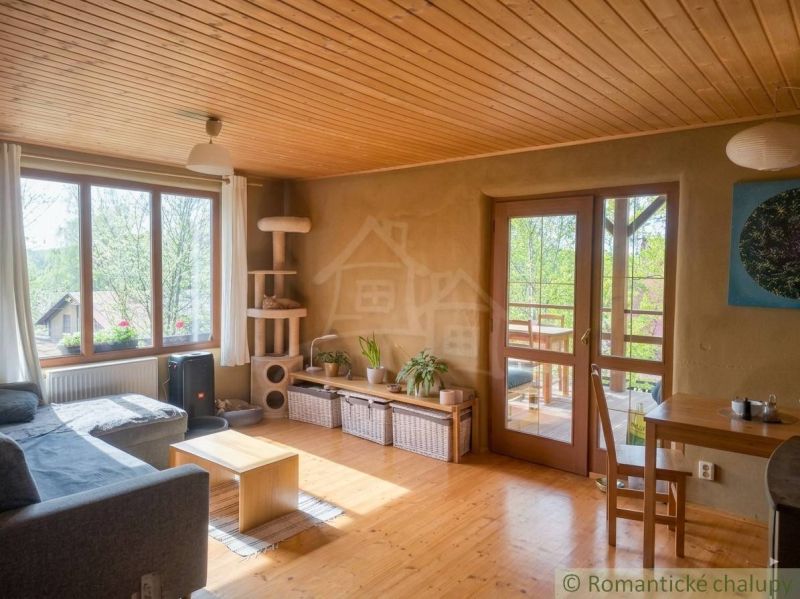 Living room with wood-patterned flooring, light furniture, and plants in a family house.
