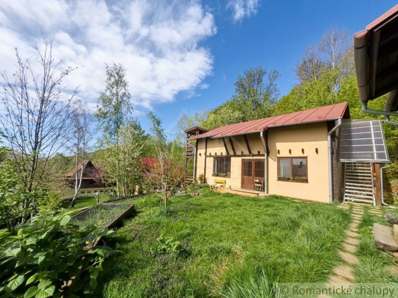 A family house in Cinobana surrounded by greenery, with a lawn and wooden terraces.