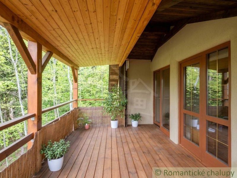 A wooden terrace in a family house in Cinobana with a view of the forest environment.