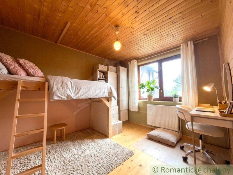 Children's room in a family house with a high bed and a desk by the window.