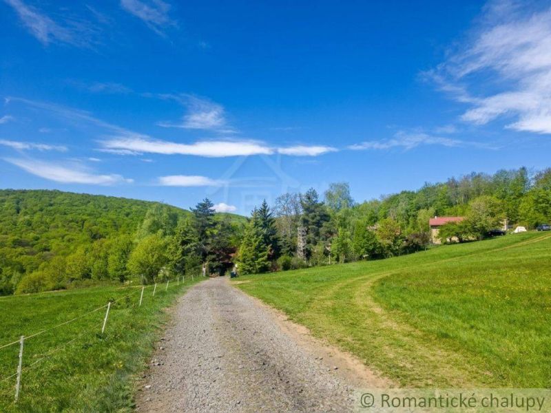 The path leads to a family house in Cinobana, surrounded by greenery and a blue sky.