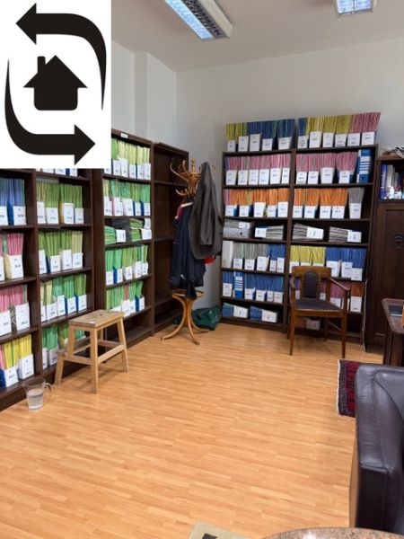 Shelving units full of binders in an office with a wood-patterned floor.