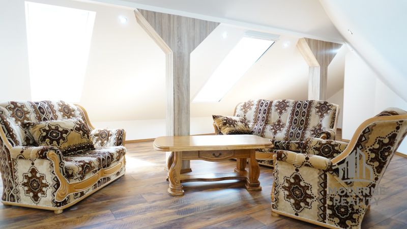 Attic living room of a 4-room apartment with comfortable armchairs and a wooden decor floor.