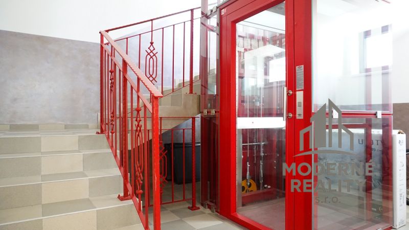 A hallway with a staircase and a red elevator in a 4-room apartment.