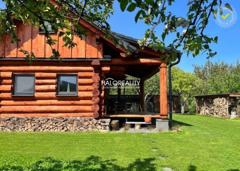 A wooden cottage surrounded by greenery in Piešťany with a well-maintained lawn and firewood.