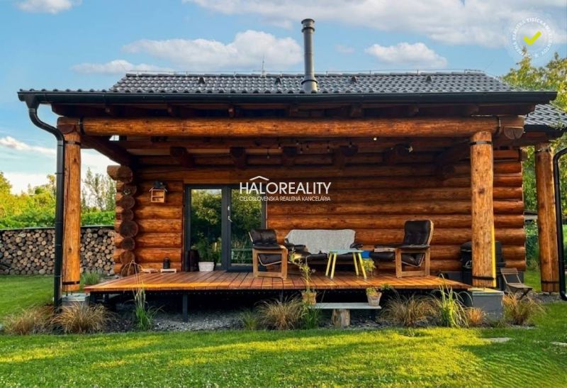 A wooden veranda of a cottage in Piešťany with comfortable chairs and greenery.