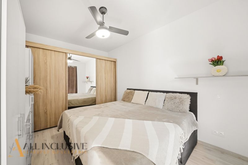 Bedroom with a double bed, wardrobe, and fan in a two-room apartment.