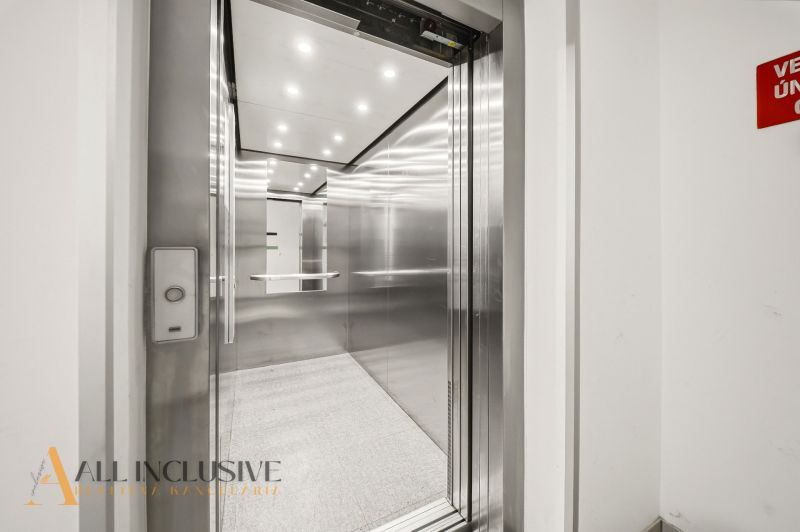Elevator in a building with shiny metal walls and a lit ceiling, 2-room apartment.