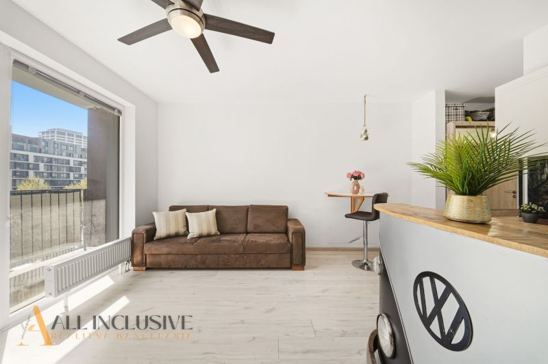 A bright living room with a brown sofa and a bar counter in a two-room apartment.