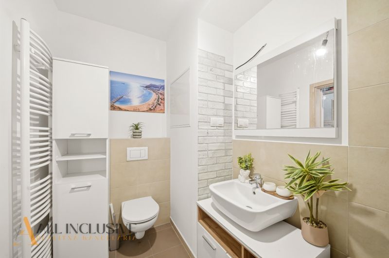 Bathroom in a 2-room apartment with a sink, toilet, and decorations.