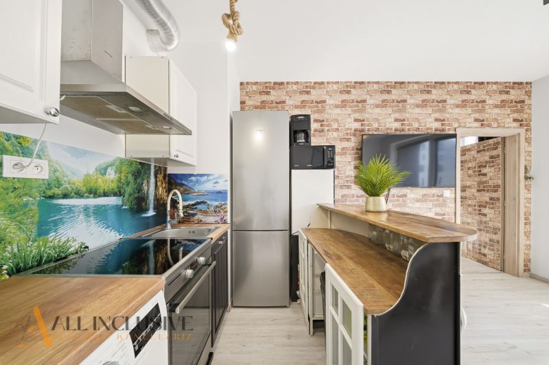 A kitchen in a 2-room apartment with brick cladding and a wooden decor floor.