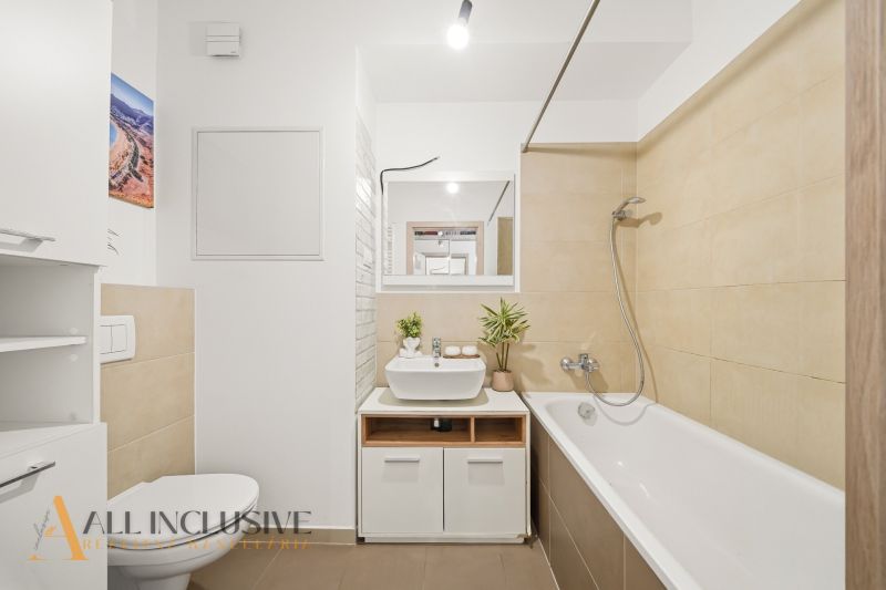 Bathroom with a shower, sink, and toilet in a 2-room apartment.