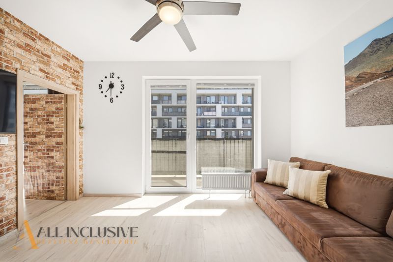 A bright living space in a 2-room apartment with a sofa and a balcony.