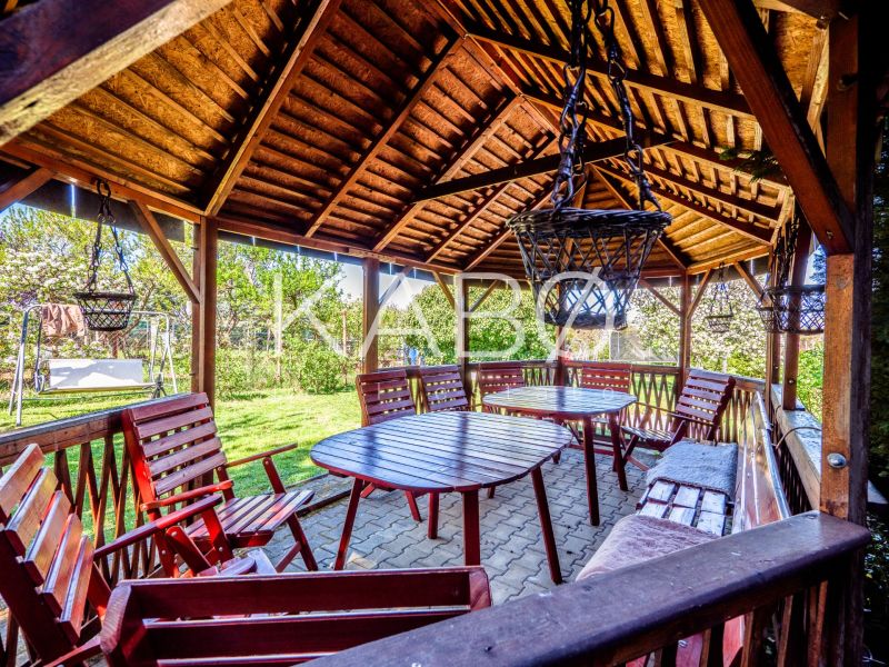 A wooden gazebo by the cottage in Nitra with seating among the trees.
