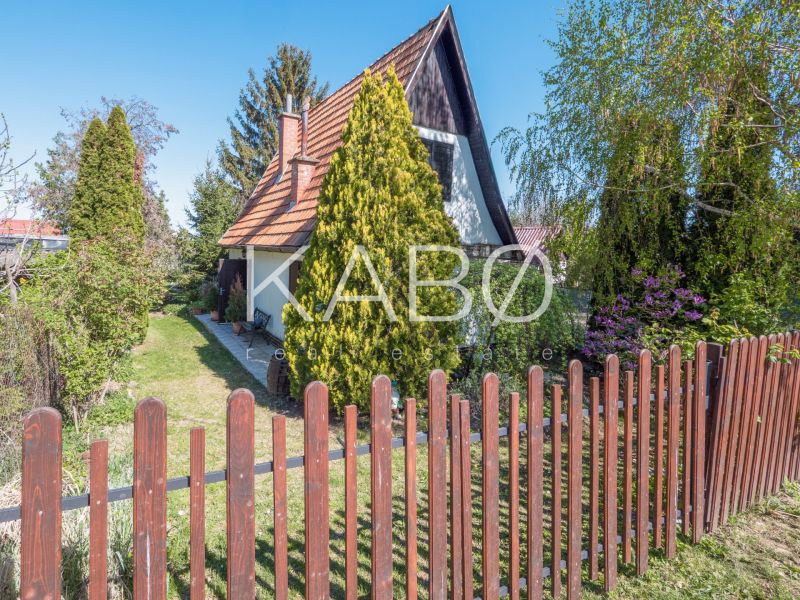 A cottage in Nitra surrounded by greenery with a wooden fence and a garden.