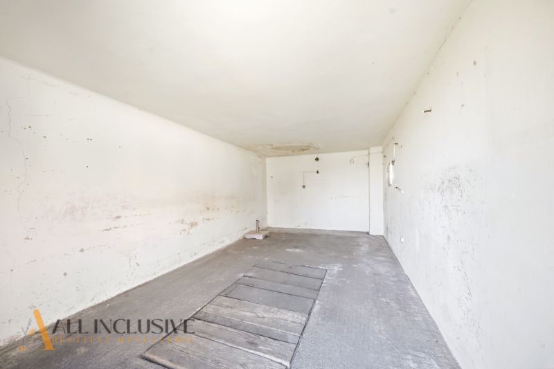 An empty room in a family house with cracked walls and a concrete floor.
