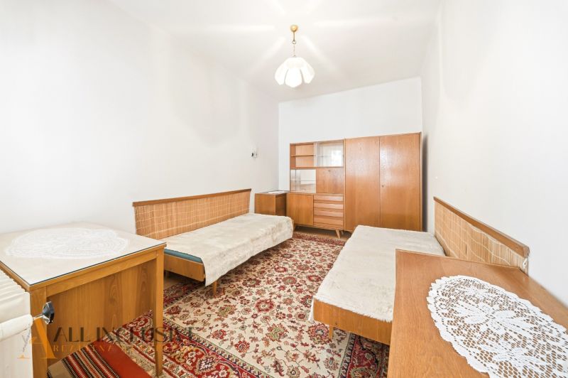 A room in a family house with carpet, wooden furniture, and two beds.