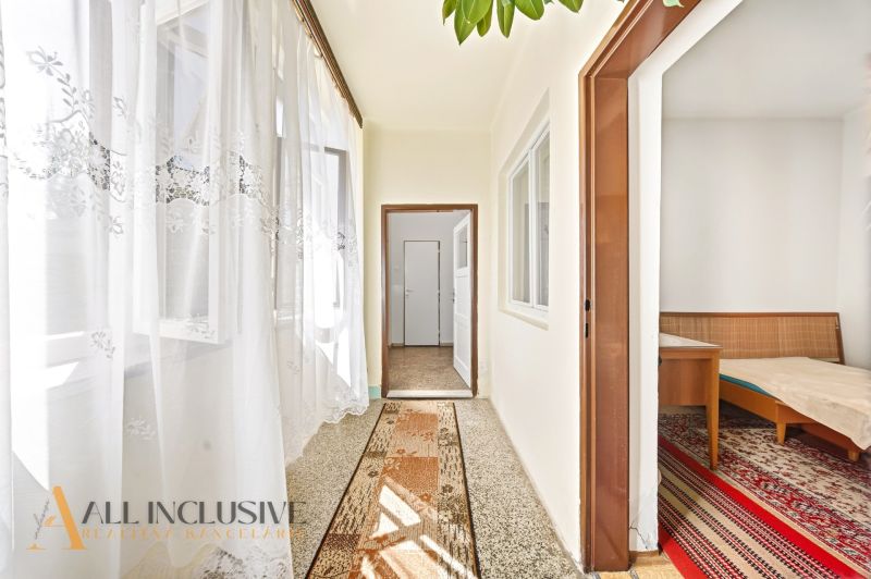 A hallway in a family house with a carpet runner and a view into the bedroom.