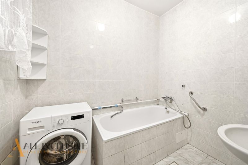 A bathroom in a family house with a bathtub, sink, and washing machine.