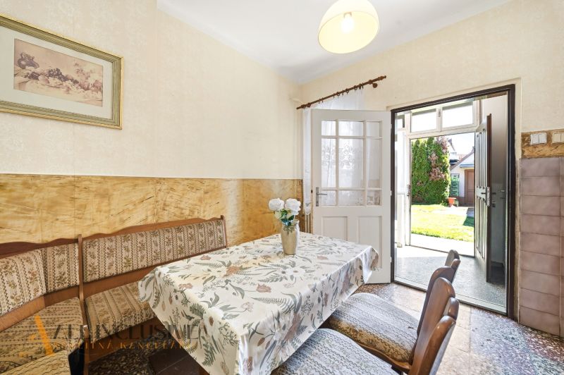 Dining room with a floral tablecloth in a family house, open doors to the garden.