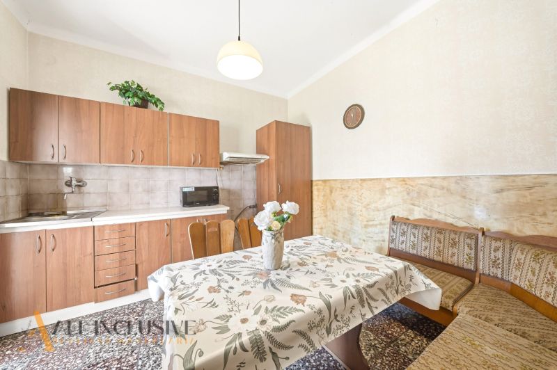 A kitchen in a family house with a kitchen unit, a dining table, and a patterned tablecloth.