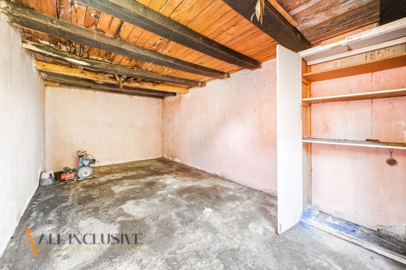 A basement in a family house with a wooden ceiling and a shelf, suitable for storage.