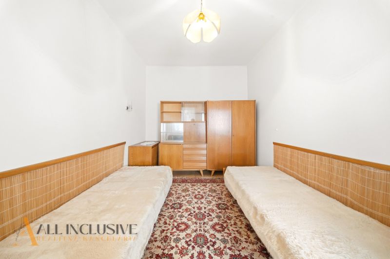 A room in a family house with two beds, a vintage cabinet, and a floral carpet.