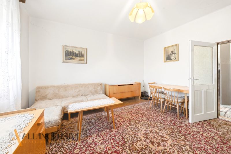 Living room in a family house with carpets, a sofa, paintings, and wooden furniture.