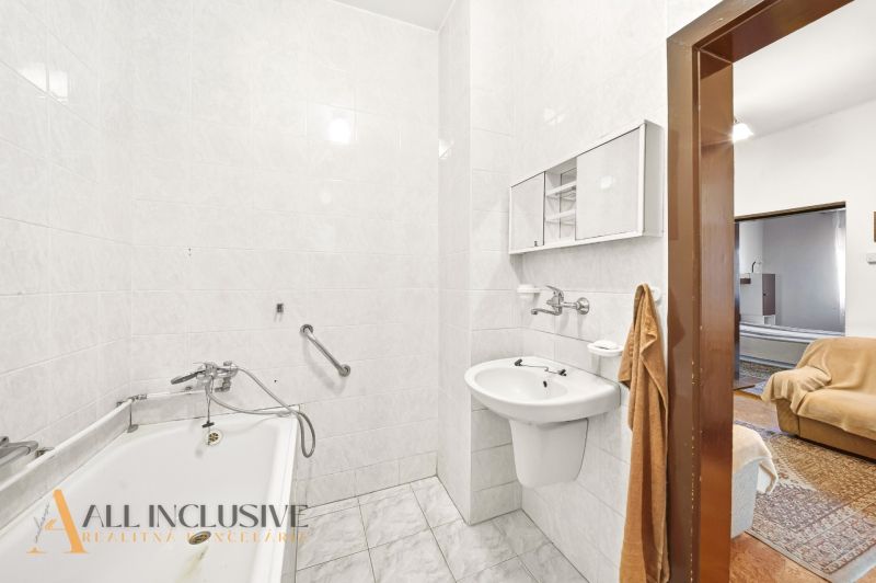 A bathroom in a family house with a bathtub and a sink, white tiles, access to the room.