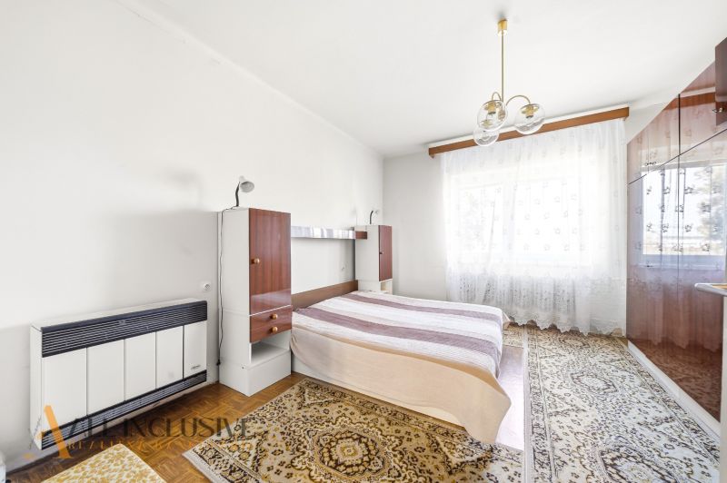 Bedroom in a family house with a bed, wardrobe, and carpets on a floor with a wooden decor.