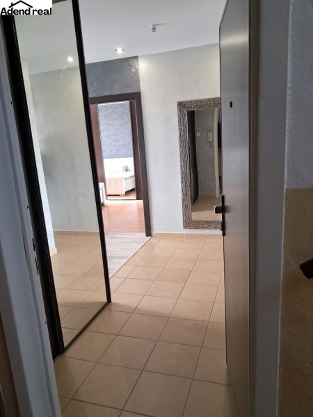 A hallway in a 2-room apartment with tiles and a mirror on the wall.