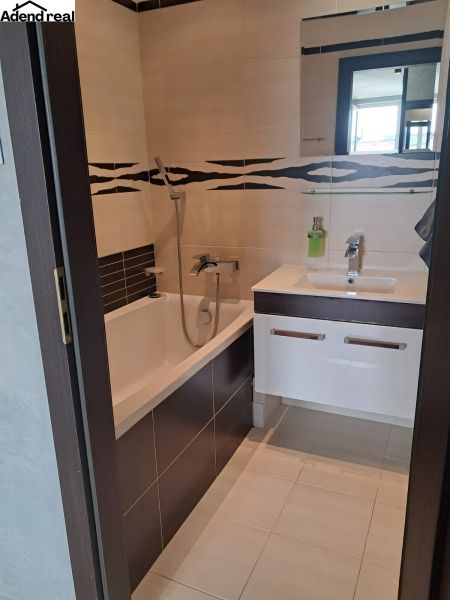 The bathroom with a shower and a bathtub in the 2-room apartment combines white and dark tiles.
