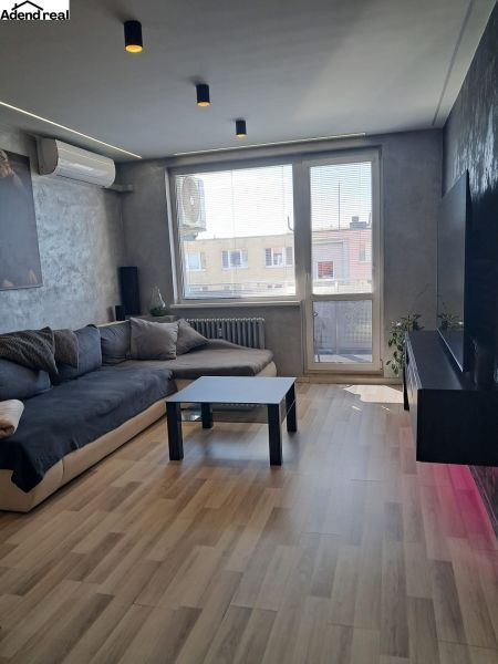 Living room with a sofa, black table, and wooden decor flooring.