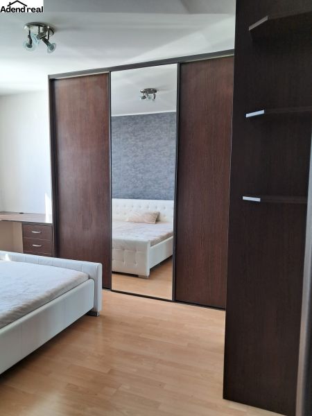Bedroom with a bed and a wardrobe with a mirror in a 2-room apartment, floor with wood decor.