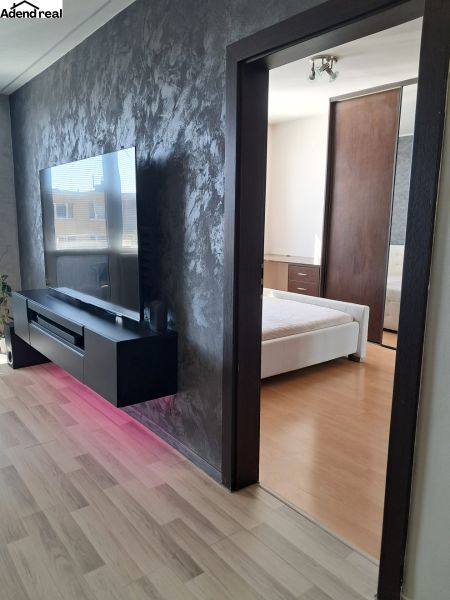 An apartment with a wooden floor decor, a television, and an entrance to the bedroom.
