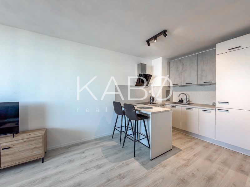 Kitchen with bar stools, bright 2-room apartment, wooden decor flooring.