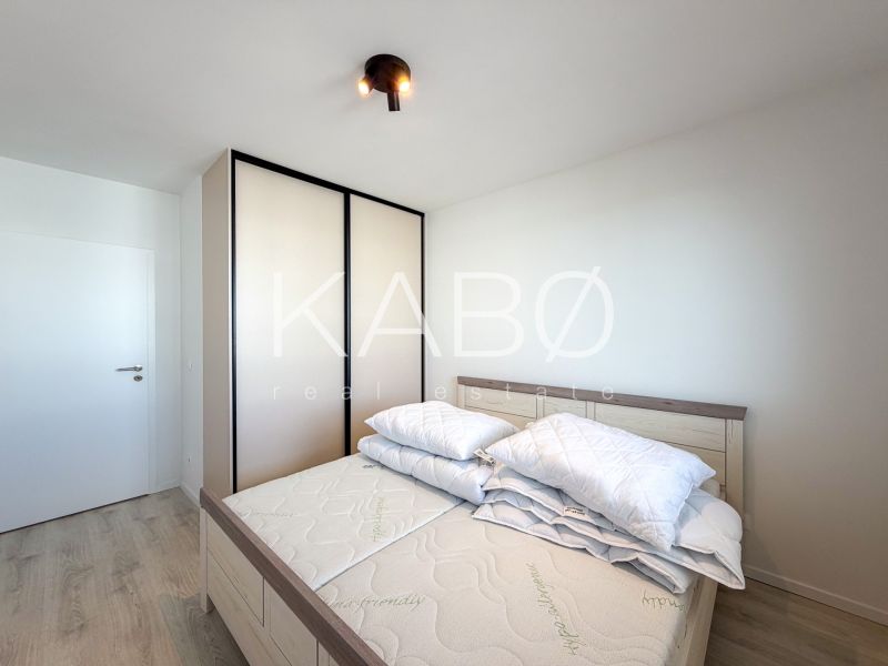 A bedroom in a two-room apartment with a wooden decor floor and a built-in wardrobe.