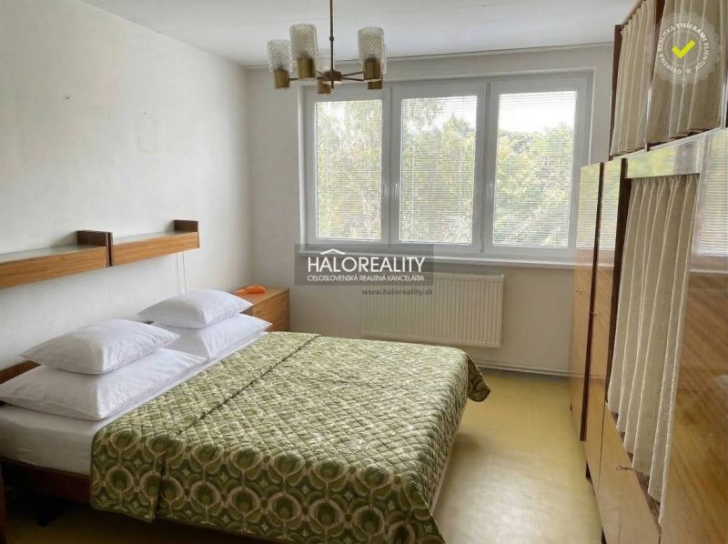 Bedroom with a bed and a cabinet in a light 3-room apartment, cream-colored walls.