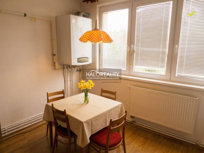 A dining room with wooden decor, a radiator, and a window in a 3-room apartment.