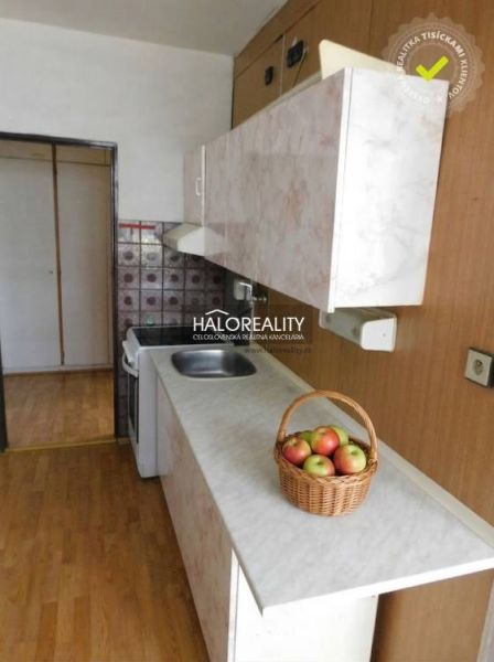 A kitchen in a 3-room apartment with a wooden decor floor and a basket of apples.