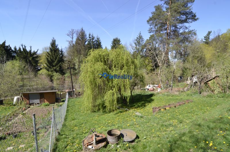 Gardens in Zvolen with plenty of greenery, trees, and a small wooden cottage.
