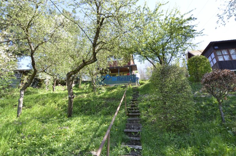 The staircase leads through a grassy garden in the city of Zvolen, surrounded by trees and shrubs.