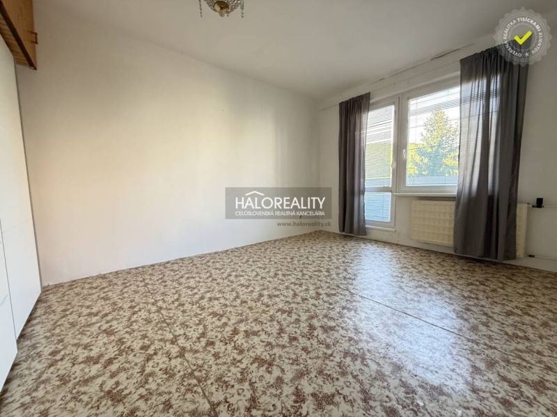 A room in a 3-room apartment with a large window and curtains, a floor with a wooden decor.