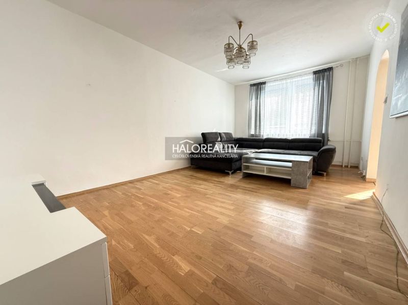 Living room in a three-room apartment with a wooden decor floor and a large sofa.