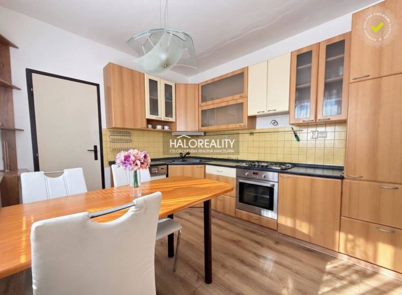 A kitchen in a 3-room apartment with a wood-patterned floor and a dining table.