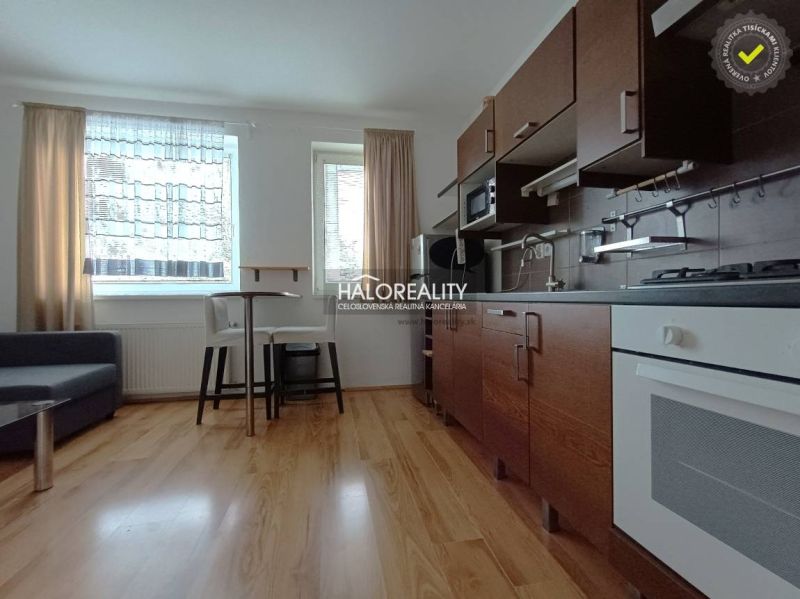 A kitchen in a 2-room apartment with a wooden decor floor and a dining area.