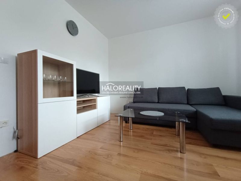 Living room in a two-room apartment with a wooden decor floor and a comfortable sofa.