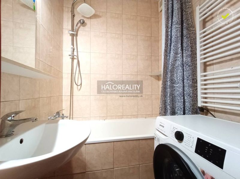 A bathroom in a 2-room apartment with a shower, bathtub, and washing machine.